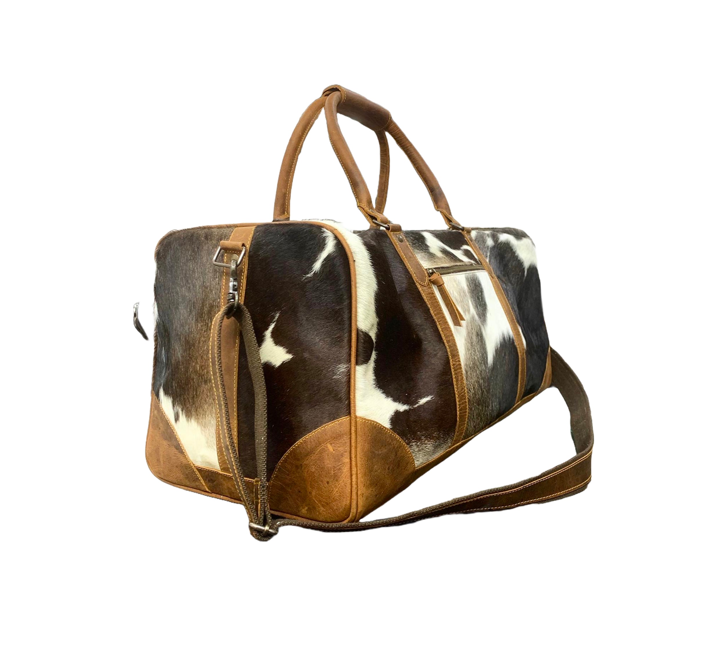 Cow print duffel bag with brown leather accents on a white background